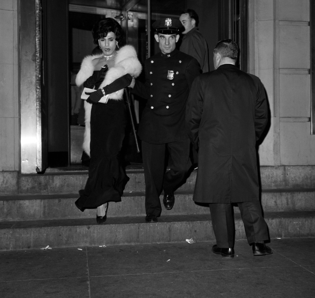 A police officer escorts a person arrested after a New York drag-ball raid in 1962.